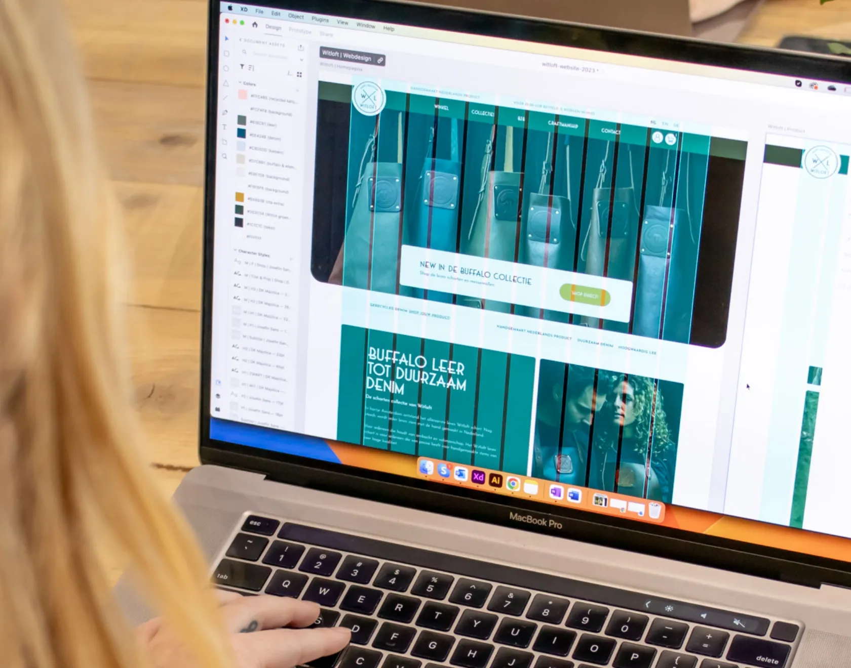 Persoon werkt aan een webdesign op maat in Adobe XD op een MacBook Pro.