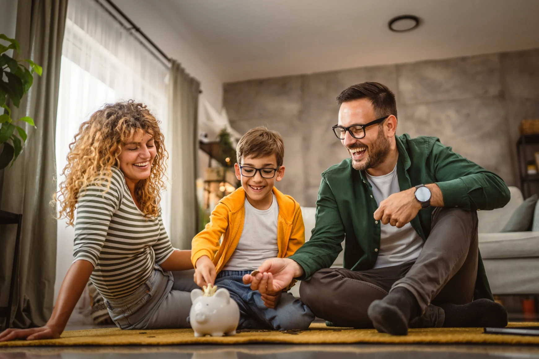 Gezin lacht samen terwijl het kind geld in een spaarvarken stopt binnen een gezellige woonkamer.