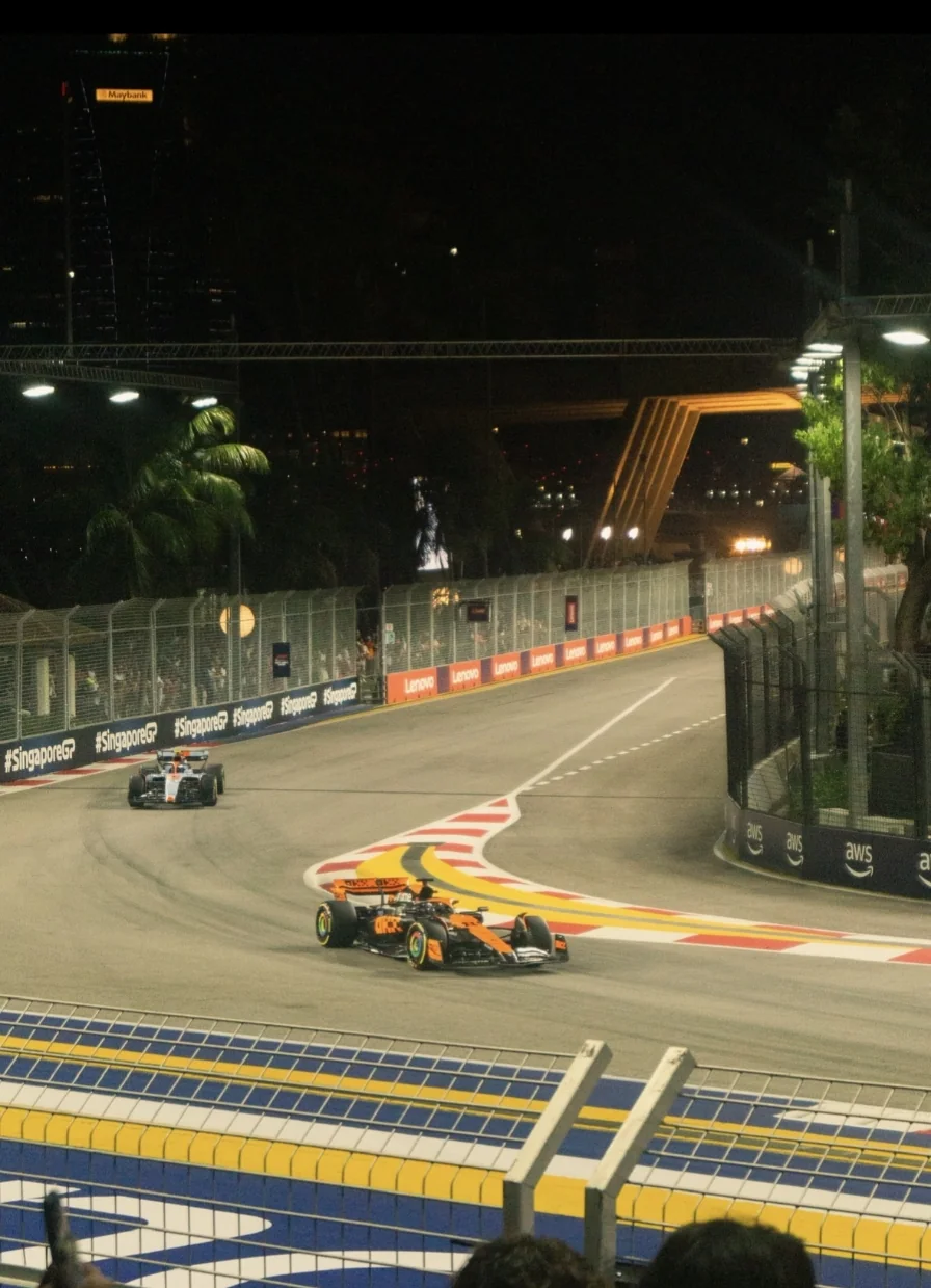 Formule 1-auto’s racen door een bocht op het verlichte stratencircuit van Singapore tijdens een nachtelijke Grand Prix.